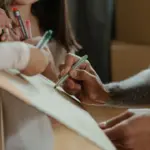 people writing on cardboard with felt tip pens