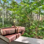 leather journals resting on a balcony railing overlooking the woods.