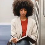Lady on the subway writing in a journal.